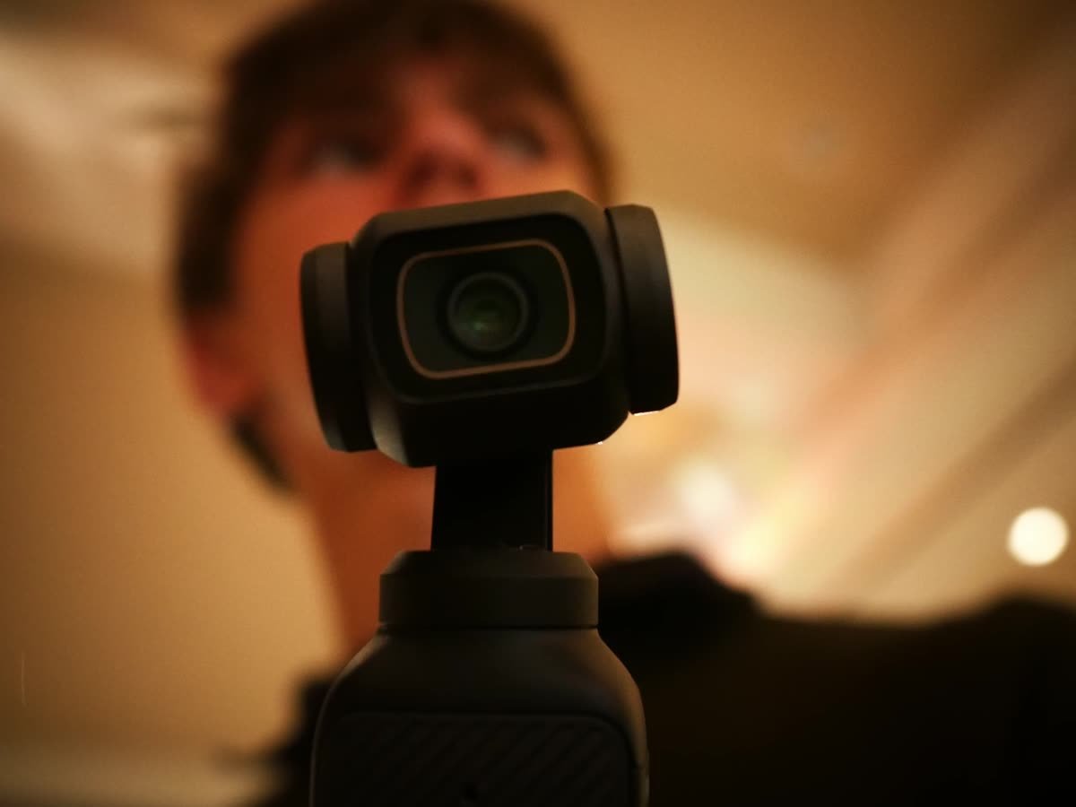 Eine kleine Gimbal-Kamera, dahinter unscharf das Gesicht der Person, die sie hält.