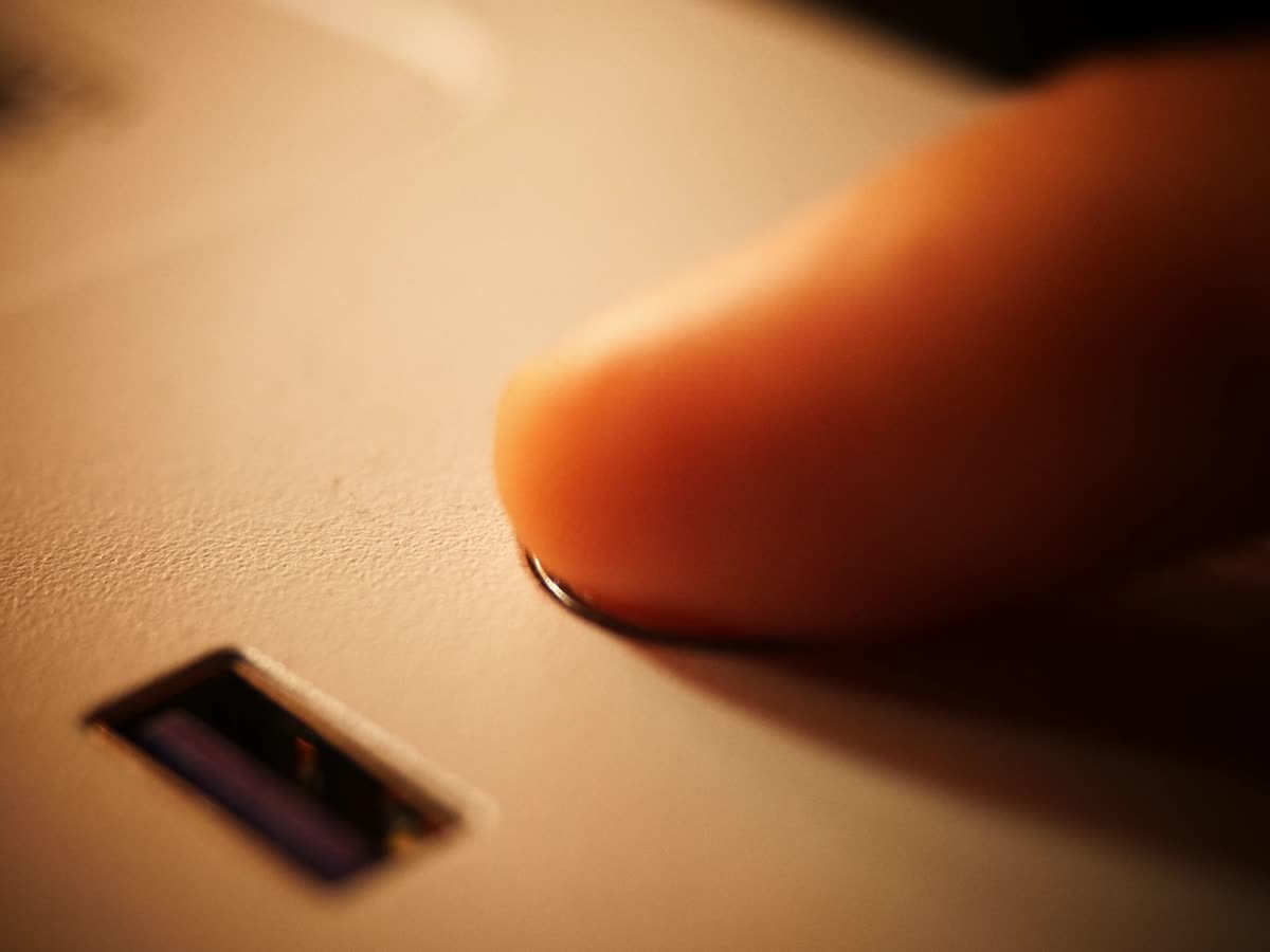 Ein Finger an einem Kameragehäuse, daneben der Schlitz für die Speicherkarte.