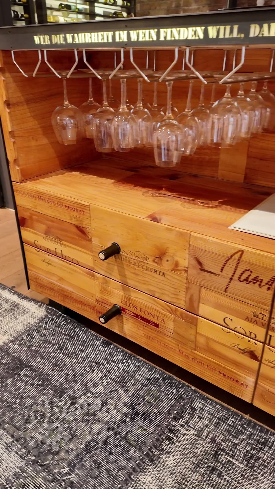 Weingläser hängen kopfüber über einem Möbel aus alten Weinkisten.